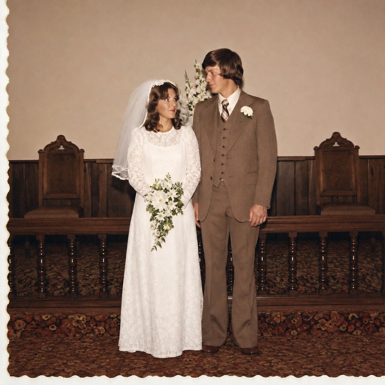 The same 1976 wedding print after restoration: ivory lace, the groom's brown suit and the red church carpet back to their real colors, the crease and scratches gone, faces and pose unchanged